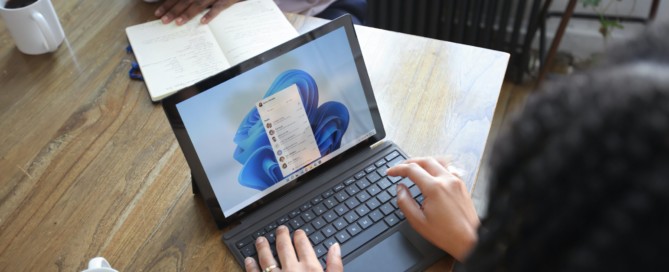 Overhead view of two people at a table working with a Microsoft laptop and notebook