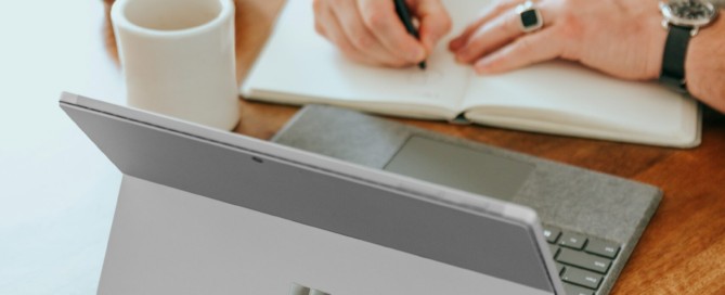 a man sitting at a table writing on a notebook