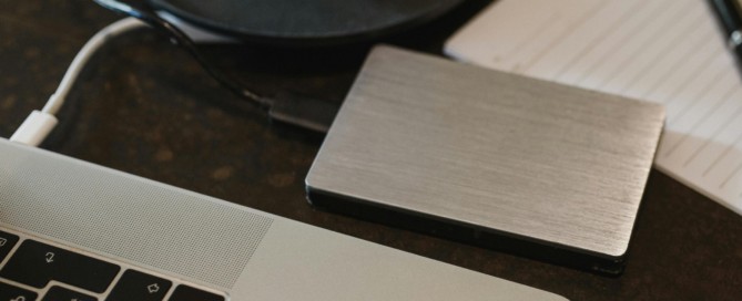 Free Closeup of an external hard drive connected to a laptop with a USB cable on a desk. Stock Photo